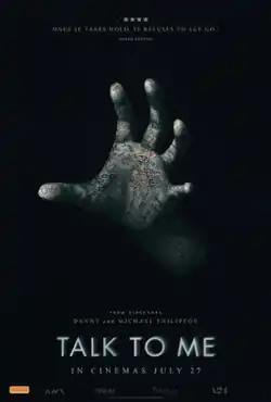 A stone hand with many writings drewn on it is seen on a dark background.