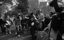 A pantomime horse is surrounded by media and police. Chaser member Chris Taylor on the obviously fake horse dressed like a police officer.