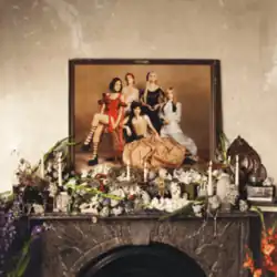 A portrait of the band atop a mantelpiece adorned with flowers and candles.