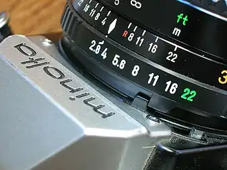 MC tab, just under the engraved f/16 on the aperture ring of the lens, engages with a corresponding tab (colored black) on the camera body.
