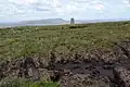 Trig point at the summit with Pendle Hill in the background.