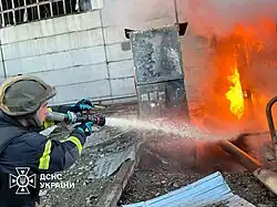 A Ukrainian firefighter extinguishing a fire using a fire hose at the Trypilska thermal power plant in Kyiv Oblast following a Russian missile attack in the night on 11 April 2024.