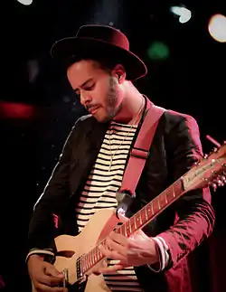 George "Twin Shadow" Lewis Jr., in his late 20s, performing on guitar.