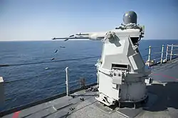 A Mk 38 MOD 2 25 mm autocannon gun system aboard the amphibious dock landing ship USS Pearl Harbor forward ejecting the spent casings.