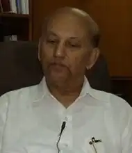 Photograph of a bald man wearing white shirt.