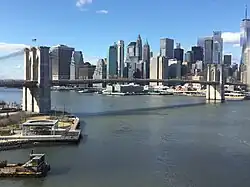 A photograph of the bridge from a similar angle as the lithograph, with the skyscrapers of Lower Manhattan in view