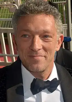 Vincent Cassel wearing a black suit and bow tie