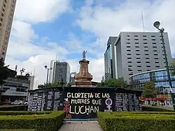 A sculpture of a woman raising her fist in the air lies on a plinth.