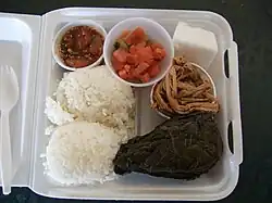 Traditional Hawaiian plate lunch. Clockwise, from bottom left: two scoops of white rice, ahi poke, lomi-lomi salmon, haupia dessert, kālua puaʻa (roast pork), and pork laulau.