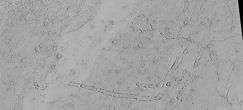 Rootless Cones, as seen by HiRISE under HiWish program. These group of rings or cones are believed to be caused by lava flowing over water ice or ground containing water ice. The ice quickly changes to steam which blows out a ring or cone. Here the kink in the chain may have been caused by the lava changing direction. Some of the forms do not have the shape of rings or cones because maybe the lava moved too quickly; thereby not allowing a complete cone shape to form. The location is the Elysium quadrangle.
