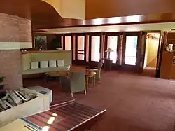 The main floor of the living room. There is built-in furniture in the foreground and floor-to-ceiling windows in the background.