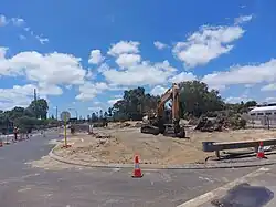 An excavator on a sandy, fenced-off construction site.