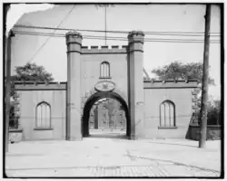 Black and white photo of a castle-like gatehouse with an arched opening