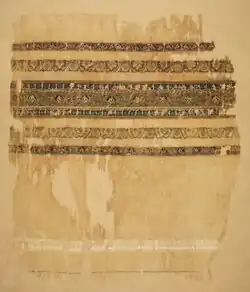 Photo of a ragged white piece of fabric with woven bands of decoration